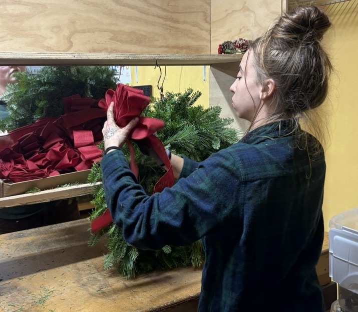 Wreath decorator in the harbor farm workshop adding decorations to wreaths.
